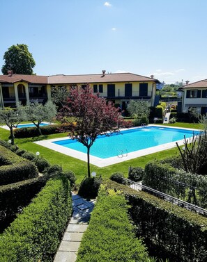A pool surrounded by well-manicured hedges and a building with a tiled roof. - A 10-minute walk from Lake Garda, quiet area, a playground 80 m (Raffa)