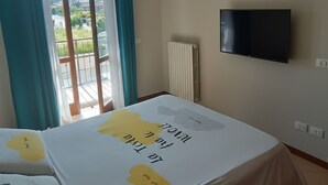 A bedroom with a bed, a TV, a radiator, and a view of the outdoors. - A 10-minute walk from Lake Garda, quiet area, a playground 80 m (Raffa)