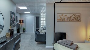 A modern bedroom with a skylight, a bed with towels, a grey sofa, a fireplace, and artwork on the walls. - The Old Post Office - UK49450 (Haltwhistle)