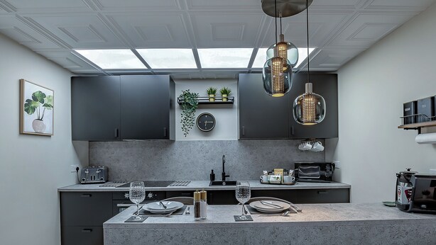 A modern kitchen with a central island, dark cabinetry, and pendant lighting. - The Old Post Office - UK49450 (Haltwhistle)