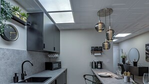 A modern kitchen with a built-in microwave, a sink, and a dining area with a table set for two. - The Old Post Office - UK49450 (Haltwhistle)