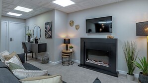 A modern living room with a fireplace, a flat-screen TV, and a sofa with decorative pillows. - The Old Post Office - UK49450 (Haltwhistle)