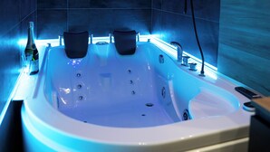 A modern bathroom with a large bathtub, a showerhead, and a bottle of champagne. - Impulses Home suite Whirlpool (Barletta)