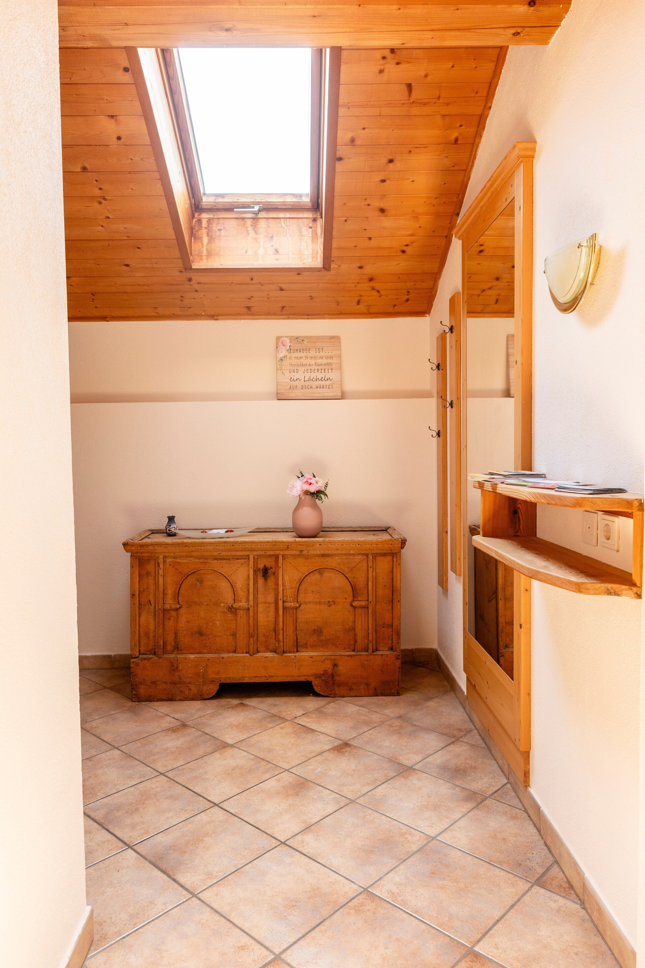 Una stanza con soffitto in legno, un lucernario, un armadietto in legno e uno specchio a parete.
