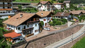 A mountainous village with traditional chalet-style houses, a stone wall, and a railway track.