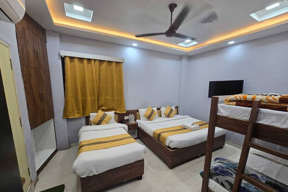 A hotel room with two beds, a ceiling fan, and a TV.