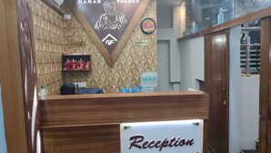 A reception desk with a sign reading "Reception" and a wall-mounted sign that says "Nanak Palace" with a "No Smoking" sign below it. - Hotel Nanak Place (Varanasi)