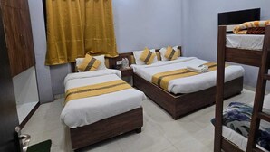 A hotel room with two beds, a ceiling fan, and a TV. - Hotel Nanak Place (Varanasi)