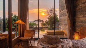 A bedroom with a large window, a bed, a chair, and a small table. - DEMI III Demi the third (Pranburi)