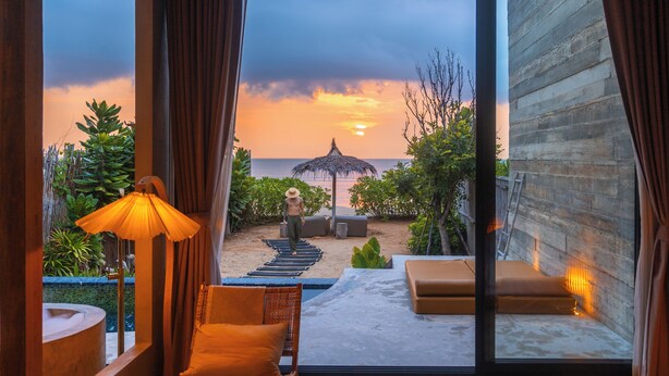 A room with a view of the beach at sunset, a thatched umbrella, and a lounge chair. - DEMI III Demi the third (Pranburi)