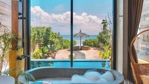 A modern bathroom with a large bathtub, a shower, and a view of a pool and beach. - DEMI III Demi the third (Pranburi)