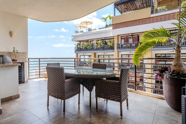 A balcony with wicker furniture, a large potted plant, and a view of the sea. - Top Views & Signature Comfort - Walk Everywhere 2BD Condo for rent in Amapas, Pu (Puerto Vallarta)