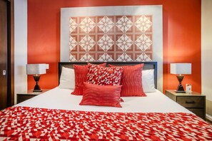 A hotel room with a large bed, red and white patterned bedding, two bedside lamps, and a geometric wall decoration. - Top Views & Signature Comfort - Walk Everywhere 2BD Condo for rent in Amapas, Pu (Puerto Vallarta)