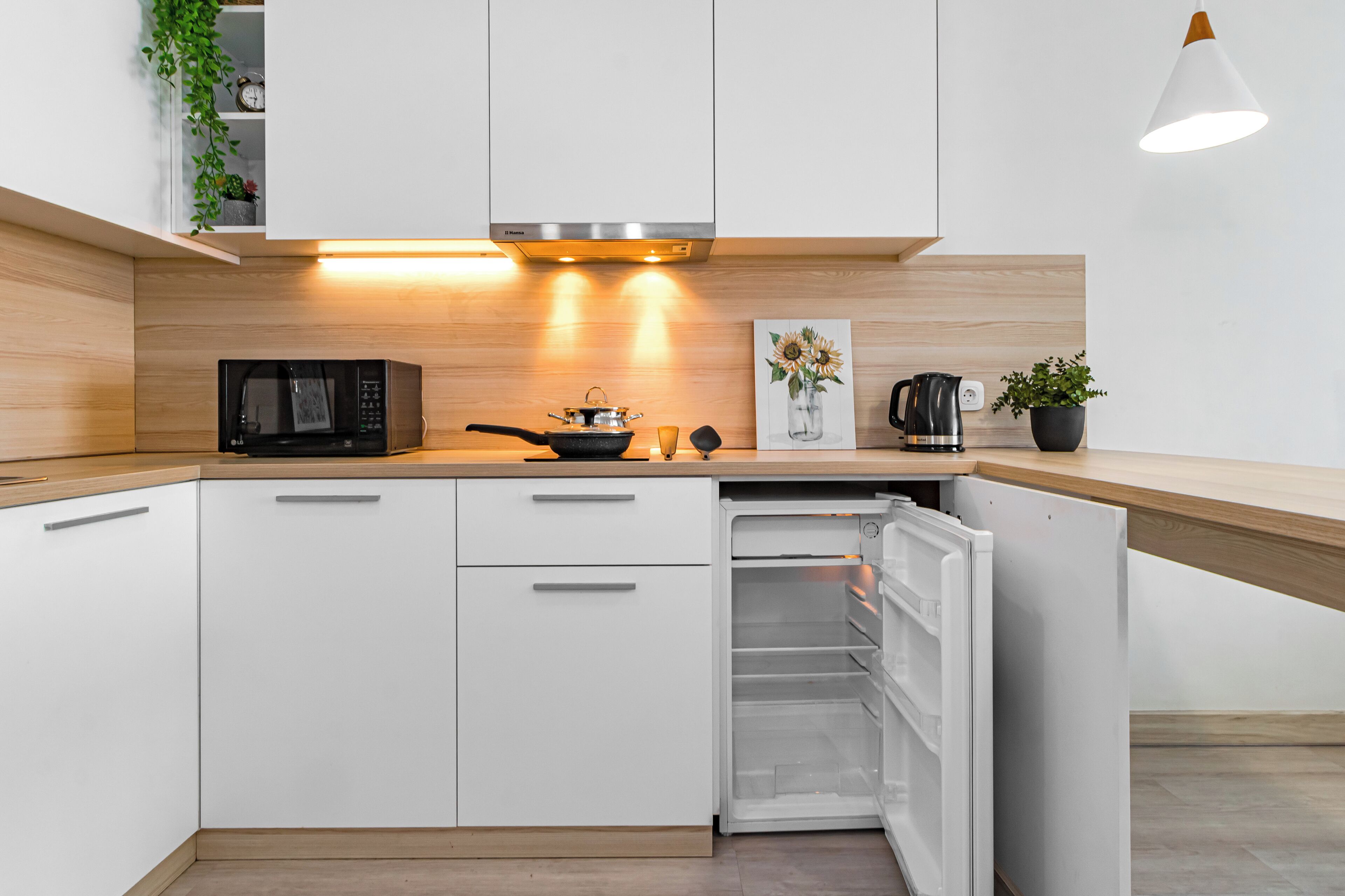 A modern kitchen with white cabinets, a microwave, a stove, and a refrigerator.