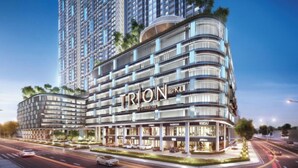 A modern hotel with a curved facade, multiple balconies, and a prominent 'TRION' sign.