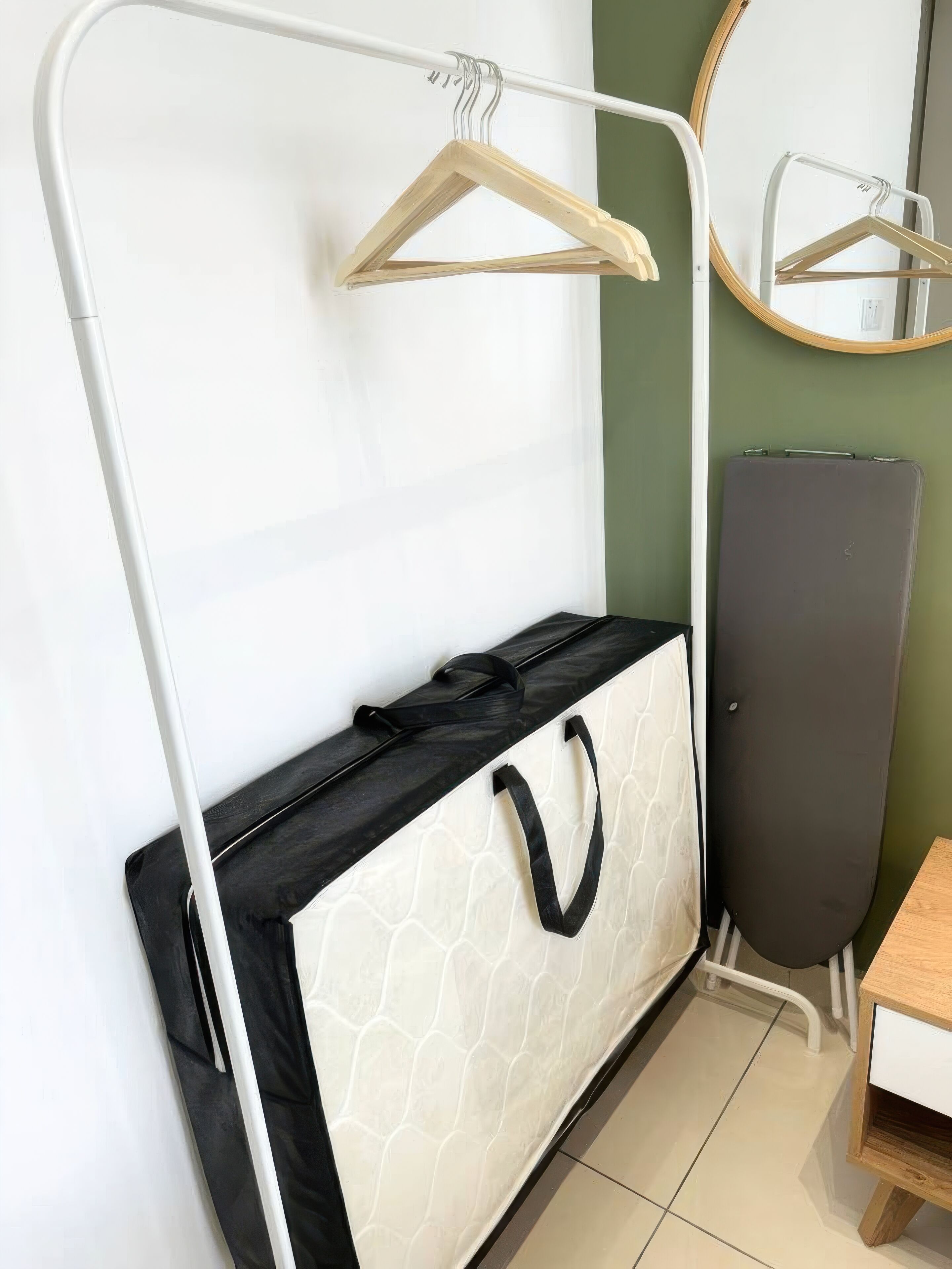 A room with a white wardrobe, a black and white storage unit, a mirror, and a wooden table.