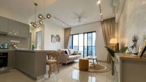 A modern kitchen with a central island, a dining area with a sofa and chairs, and a large window providing a city view.