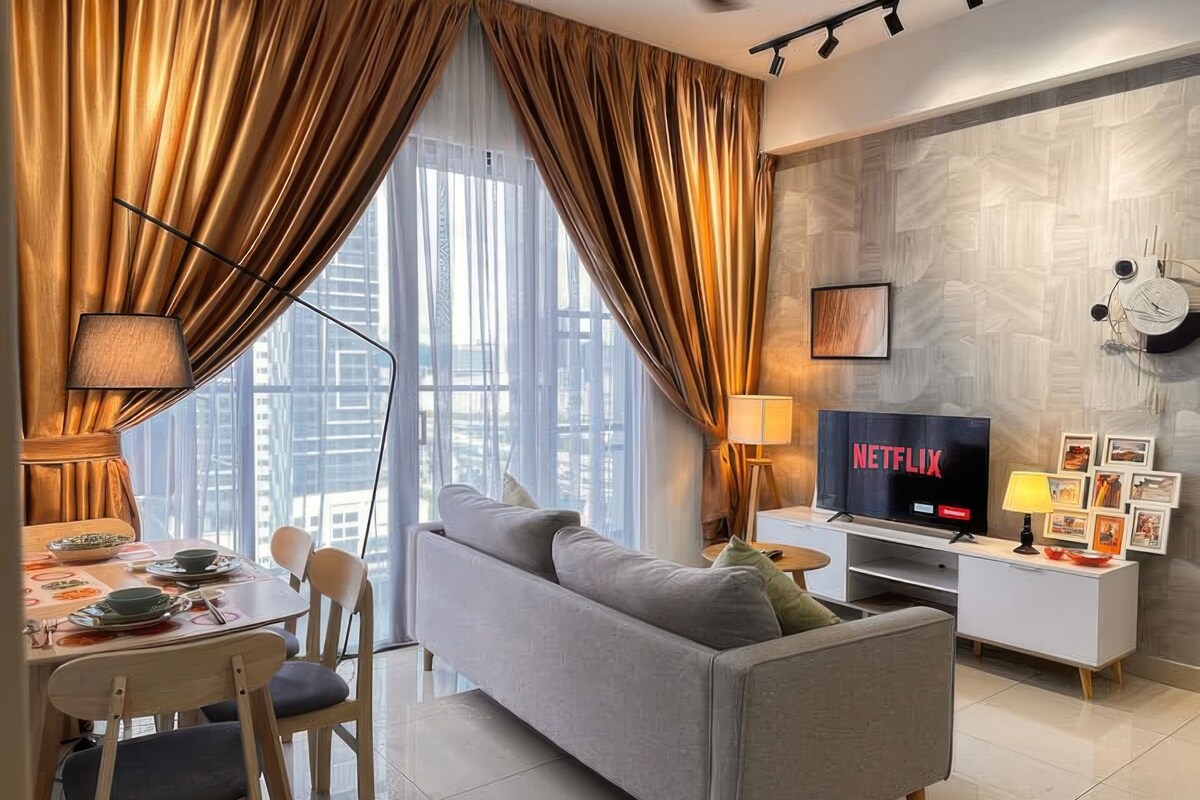 A modern living room with a sofa, TV, dining table, and curtains.