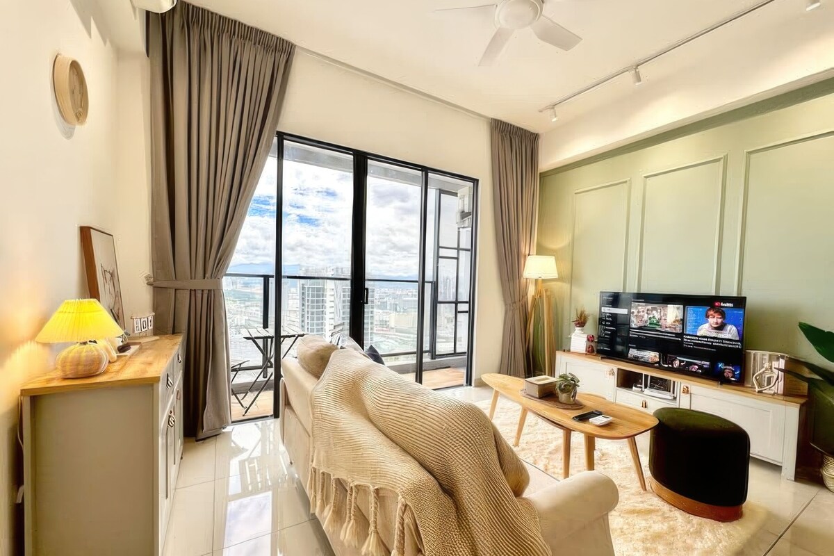 A modern living room with a sofa, a coffee table, a TV, and a balcony with a city view.
