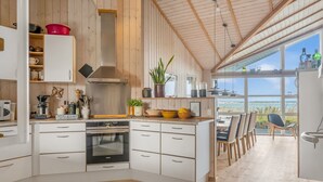 Une cuisine moderne avec des armoires blanches, un four encastré et une grande fenêtre donnant sur un paysage magnifique.