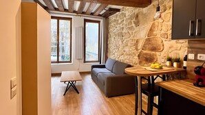 Eine moderne Küche mit Steinwänden, Holzboden und einer Akzentwand aus Stein. Ein Essbereich mit Tisch und Stühlen, sowie eine Couch im Hintergrund.