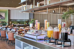 A buffet area with various food and drink options, including fruit, juices, and a coffee station.