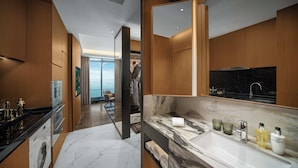 A modern hotel bathroom with a large mirror, marble countertop, and a view of the sea through the glass door. - MaxX Harbour-view Qingdao (Qingdao)