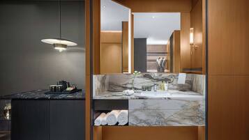 A modern bathroom with a marble vanity, wooden cabinetry, and a hanging light fixture.