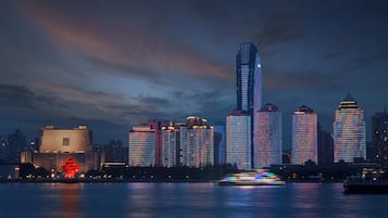 Un horizonte urbano al anochecer con edificios iluminados y su reflejo en el agua.