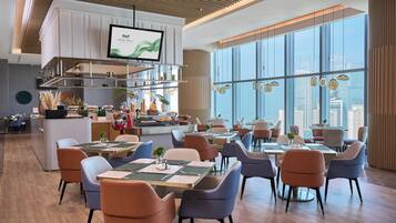 A modern restaurant with high ceilings, large windows, and a city view.