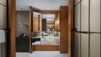 A modern bathroom with a marble vanity, wooden cabinets, and a towel rack.