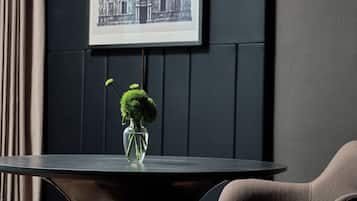 Et moderne værelse med et mørkt træbord, en vase med grønne planter, et indrammet billede på væggen og en brun stol.
