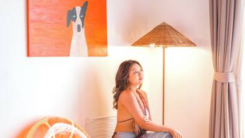 A room with a bed, a wall-mounted artwork of a dog, a floor lamp, and a large orange inflatable ring.