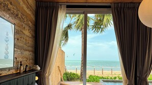 A bedroom with a bed, a wooden headboard, a view of the beach, and a pool. - Furusato Shack (Pranburi)
