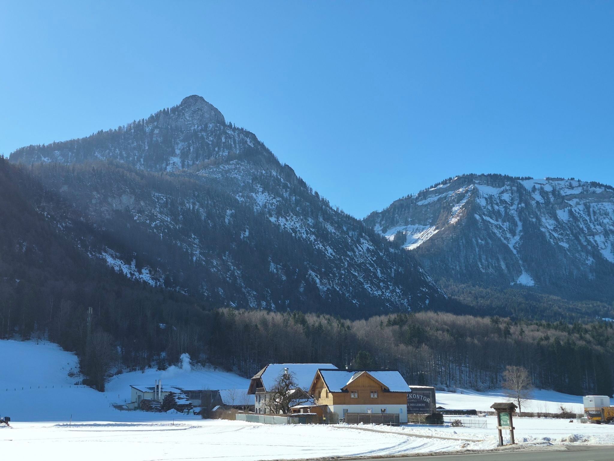 A mountain lodge with a wooden exterior, a snow-covered landscape, and a clear blue sky.