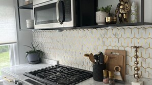 A modern kitchen with a built-in oven, microwave, and gas stove. There are cabinets, a shelf with decorative items, and a patterned backsplash. - Modern 1 bedroom apartment near Stony Brook university hospital walking distance (Stony Brook)