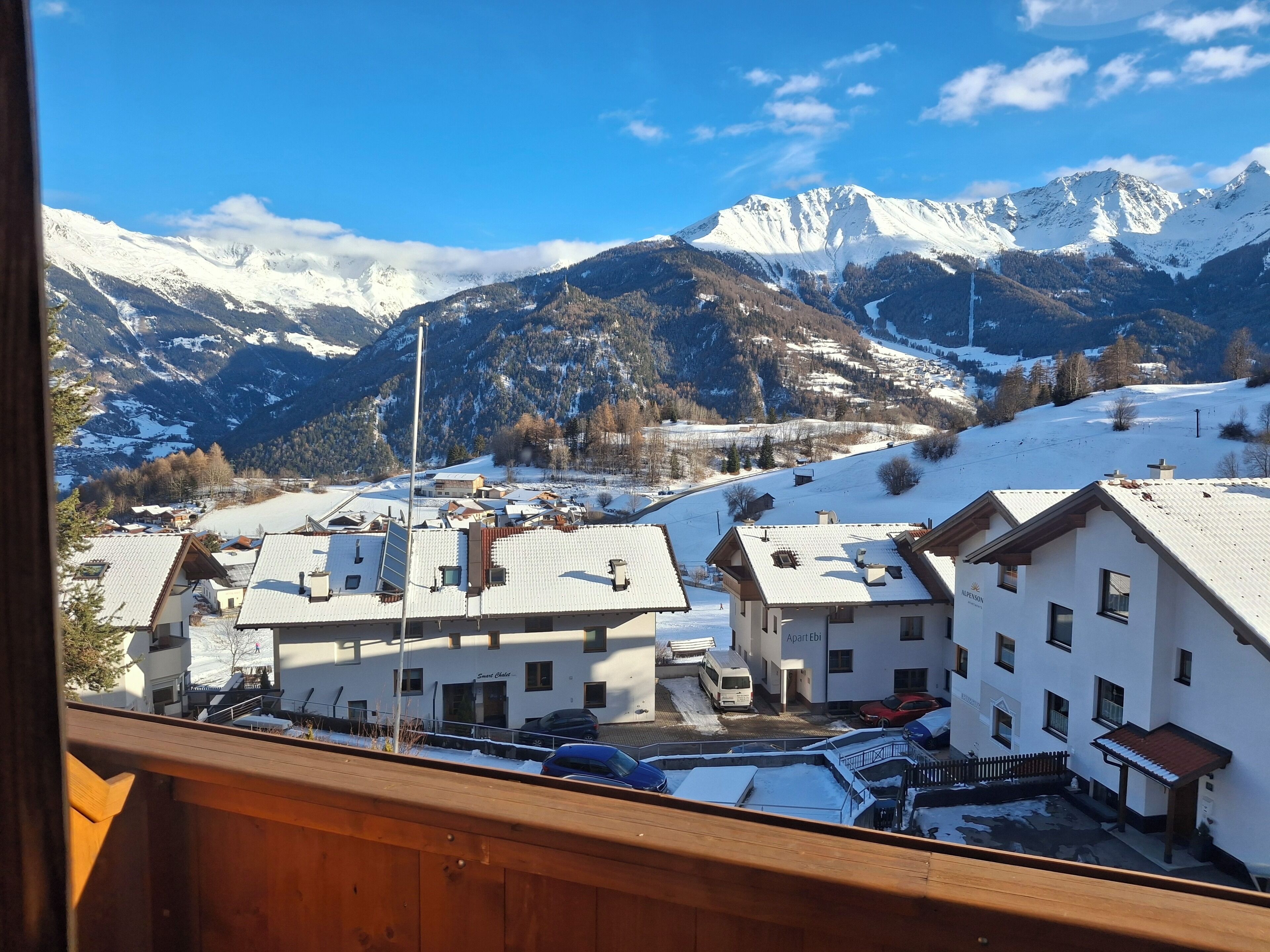 Vista de un pueblo de montaña con edificios cubiertos de nieve y cielo despejado.