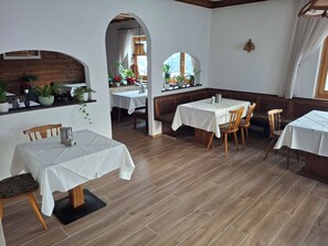 A restaurant with wooden flooring, white tablecloths, and wooden chairs. - Pension Razil (Ladis)
