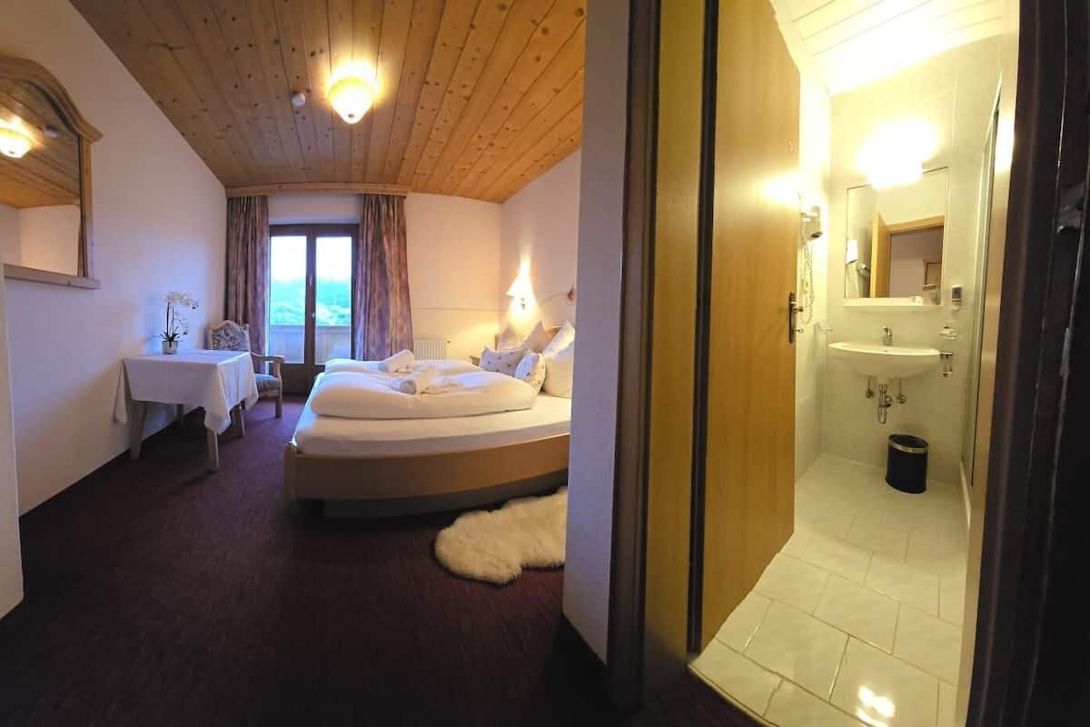 Ein Hotelzimmer mit Bett, Nachttisch und Blick ins Freie durch ein Fenster.