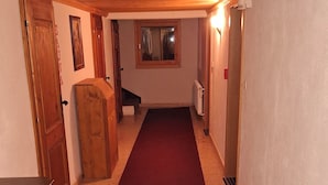 Un couloir avec un tapis rouge, des portes en bois et un radiateur.