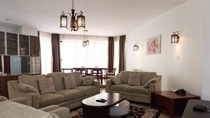Un salon moderne comprenant un ensemble de canapés, une table basse et un coin repas agrémenté d’un lustre.