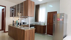 Une cuisine moderne avec des meubles en bois, un îlot central intégré, des appareils électroménagers en acier inoxydable et un grand réfrigérateur.