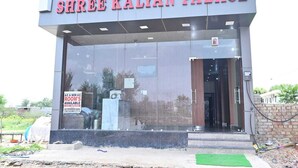 The exterior of Shree Kalyan Palace with a large glass window, a sign indicating room availability, and a brick wall to the right. - Shree Kalyan Palace (Danta Ramgarh)
