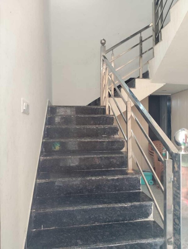 A staircase with black steps and a metal railing. - Shree Kalyan Palace (Danta Ramgarh)