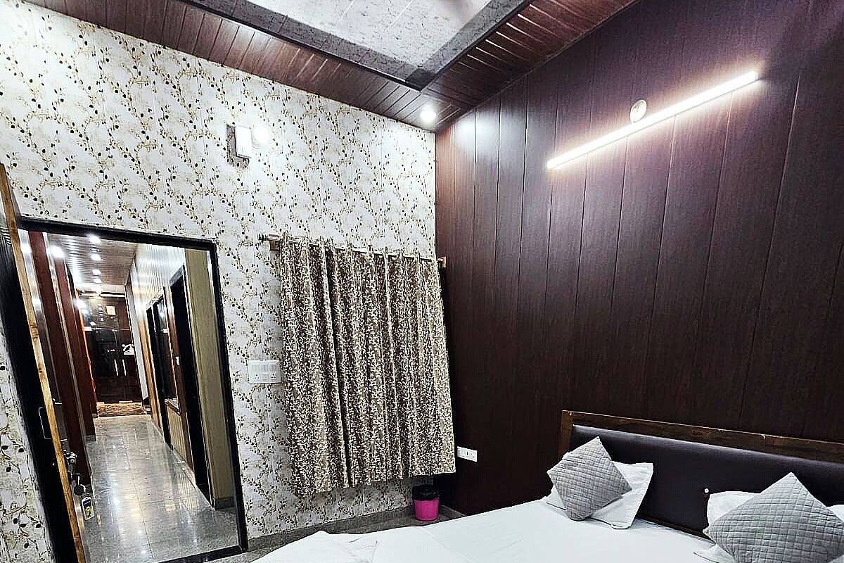 A modern bedroom with a large bed, dark wooden paneling, a mirror, and a patterned curtain.