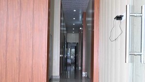 A corridor with polished marble floors, wooden paneling on one side, and a metal door on the other. - Shree Kalyan Palace (Danta Ramgarh)