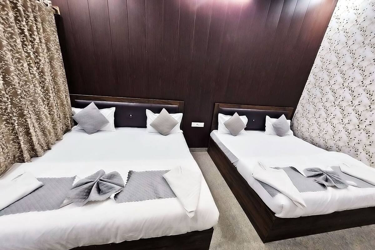 Two double beds with dark headboards, white bedding, and grey pillows.