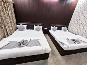 Two double beds with dark headboards, white bedding, and grey pillows. - Shree Kalyan Palace (Danta Ramgarh)