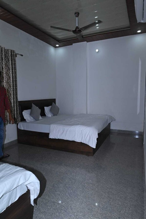 A bedroom with a bed, a ceiling fan, and a carpeted floor. - Shree Kalyan Palace (Danta Ramgarh)