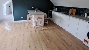 Una cocina moderna con una pared de acento oscura, suelo de madera y muebles de cocina blancos.